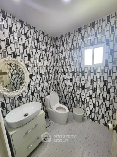 Modern bathroom with unique black and white tile design and elegant fixtures.