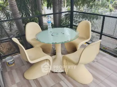 Charming outdoor balcony with modern seating and lush greenery view.
