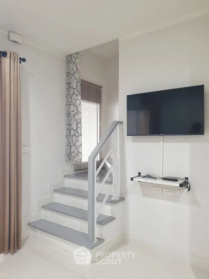 Modern interior with sleek staircase and wall-mounted TV in a stylish living space.