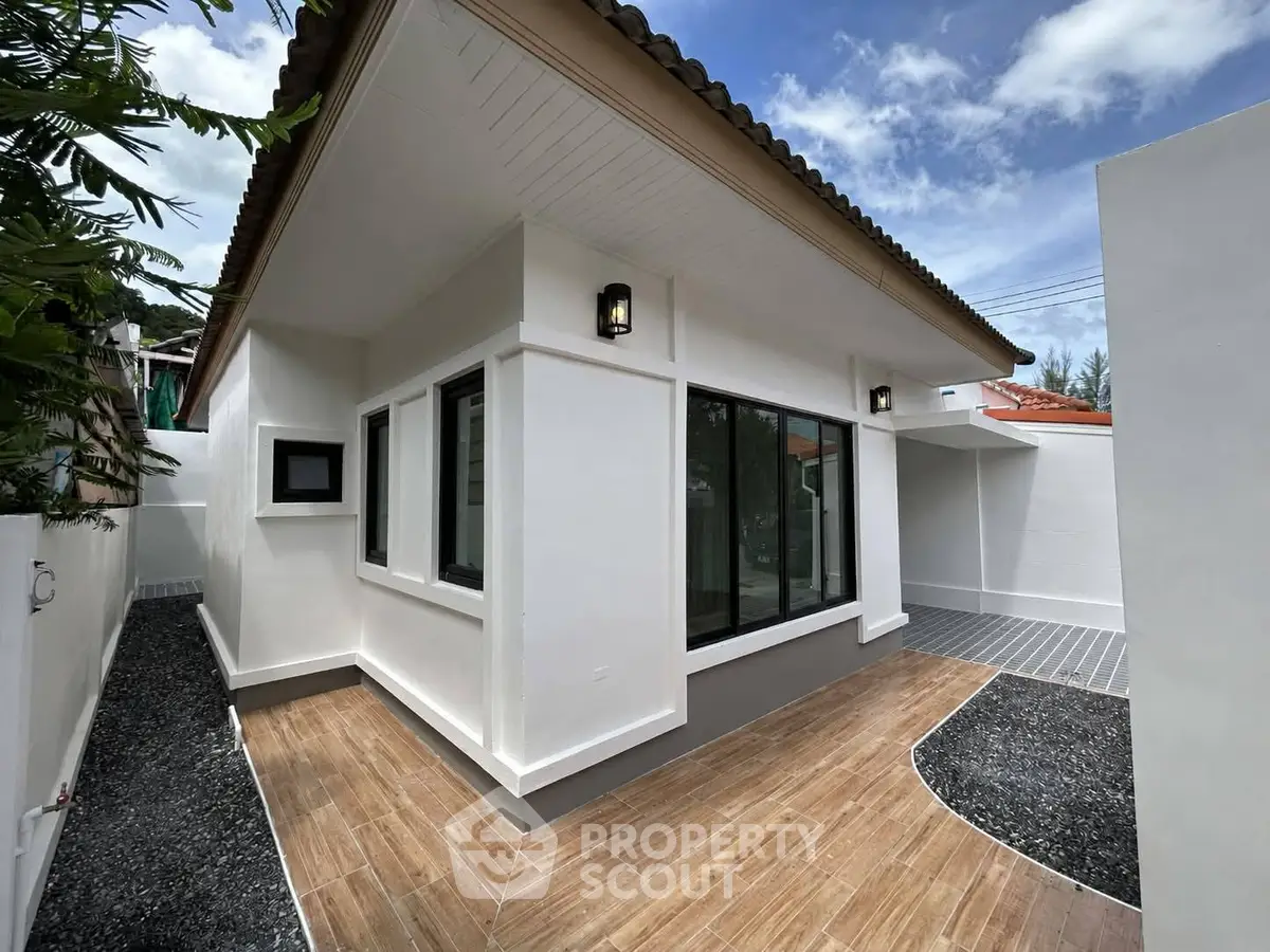 Modern single-story house with sleek design and large windows, surrounded by a neat garden path.