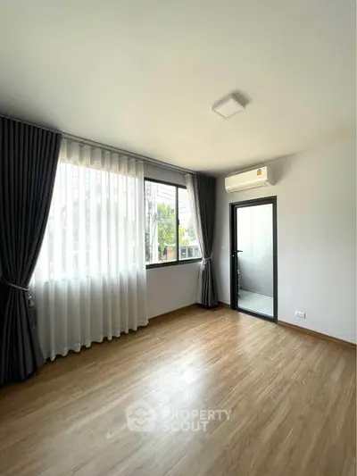 Bright and airy bedroom with large windows and modern air conditioning unit.
