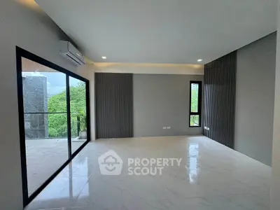 Spacious modern living room with large windows and balcony access, featuring sleek design and natural light.