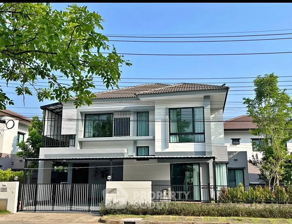 Modern two-story house with sleek design and lush greenery in a suburban neighborhood.