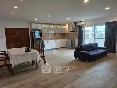 Spacious open-plan living room and kitchen with modern furnishings and ample natural light.