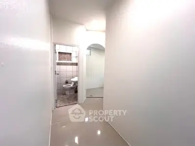 Bright hallway leading to a modern bathroom with sleek tiles and minimalist design.