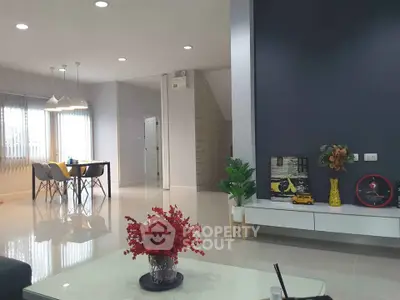 Modern living room with stylish decor and dining area, featuring sleek furniture and bright lighting.