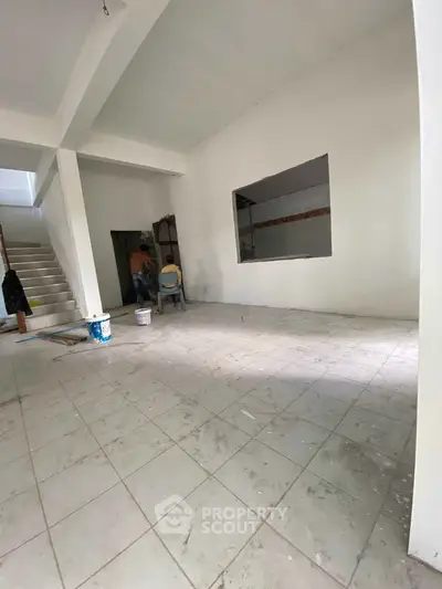 Spacious under-construction interior with tiled flooring and staircase, ideal for customization.