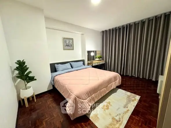 Spacious bedroom with elegant decor and cozy ambiance, featuring a large bed and stylish curtains.