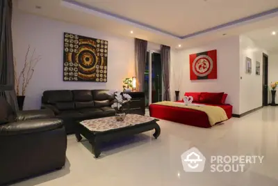 Spacious and modern living area seamlessly connected to a cozy bedroom, featuring sleek furnishings and vibrant artwork.