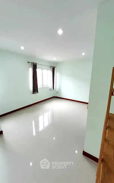 Spacious empty room with large window and glossy tiled floor