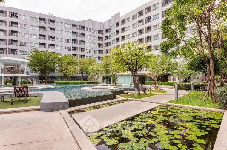 Modern apartment complex with lush garden and inviting pool area.