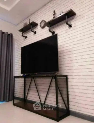 Modern living room with sleek TV stand and industrial shelves on white brick wall.