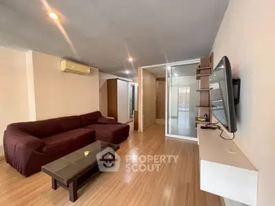 Spacious living room with modern furnishings and sleek wooden flooring.