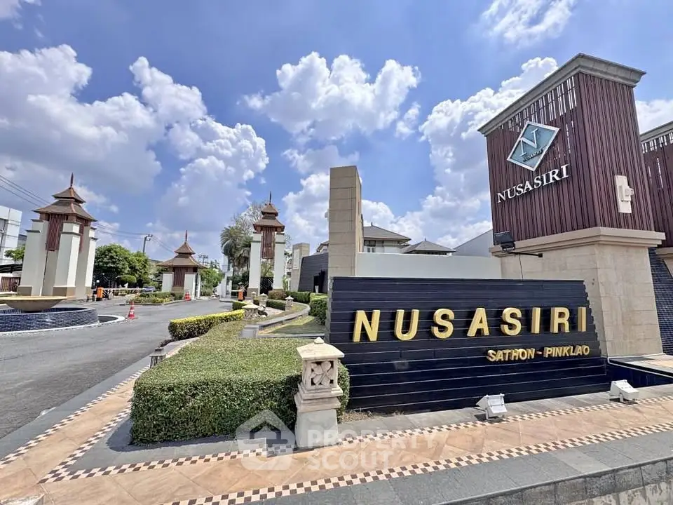 Luxurious entrance of Nusasiri Sathorn-Pinklao with elegant architecture and lush landscaping.