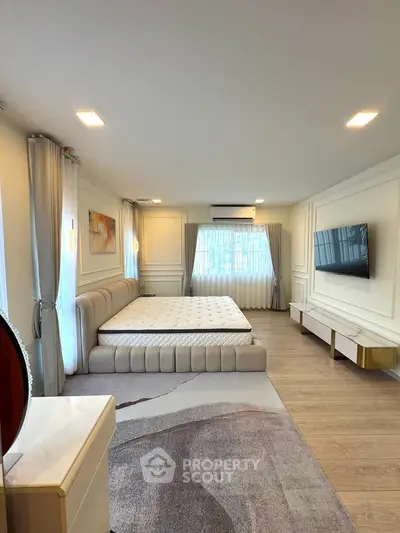 Luxurious bedroom with modern decor, large bed, and wall-mounted TV in a spacious setting.