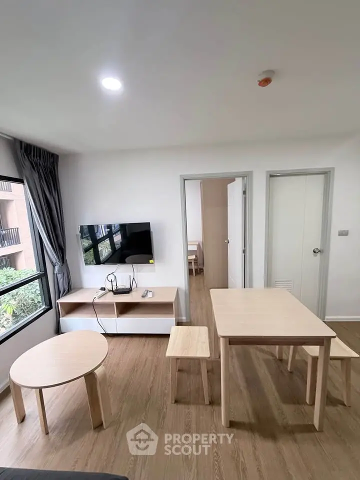 Modern living room with wooden furniture and wall-mounted TV in a bright apartment.