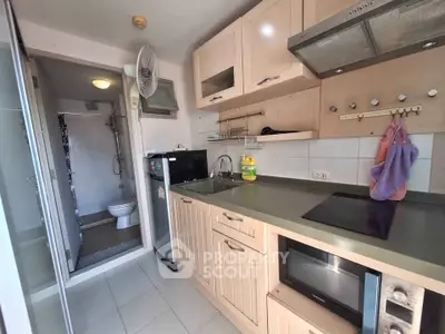 Compact kitchen with modern appliances and adjacent bathroom in cozy apartment.