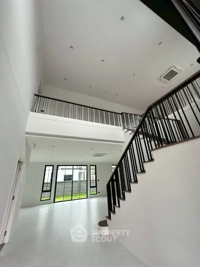Spacious modern living room with high ceilings and elegant staircase