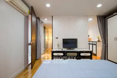 Modern bedroom with sleek design, featuring a TV, air conditioning, and elegant decor.