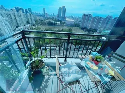 Stunning city view from a modern balcony with cozy seating and lush plants, perfect for relaxation.
