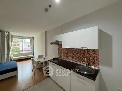 Modern studio apartment with open kitchen and bright living area, featuring a cozy bed and dining space.