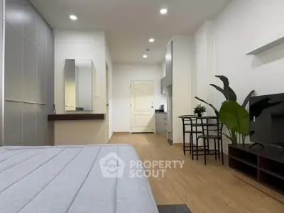 Modern studio apartment with sleek design, featuring a cozy bed, compact kitchen, and stylish decor.