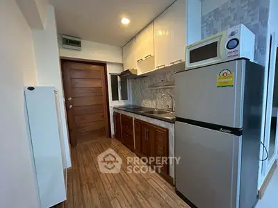 Modern kitchen with wooden cabinets and stainless steel appliances in a cozy apartment.