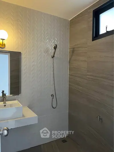 Modern bathroom with sleek design featuring a wall-mounted sink and shower area.