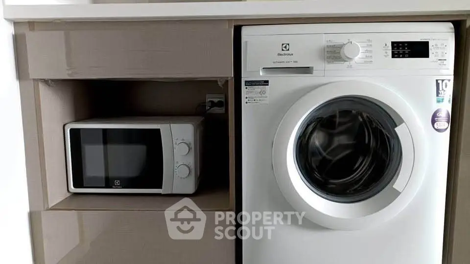 Modern kitchen with built-in microwave and washing machine in sleek cabinetry.