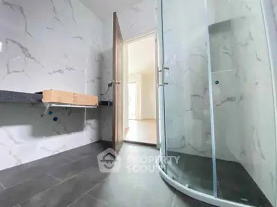 Modern bathroom with marble walls and glass shower enclosure