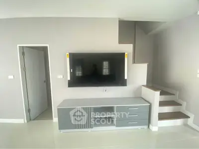 Modern living room with sleek TV unit and staircase, perfect for contemporary living.