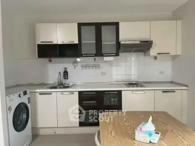 Modern kitchen with sleek cabinetry, built-in oven, and washing machine, perfect for urban living.