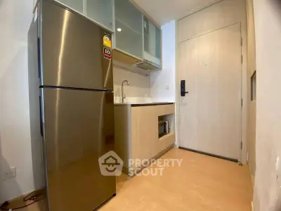 Compact modern kitchen with stainless steel fridge and sleek cabinetry