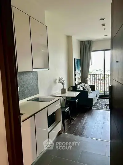 Modern apartment with compact kitchen and cozy living area featuring a balcony view.