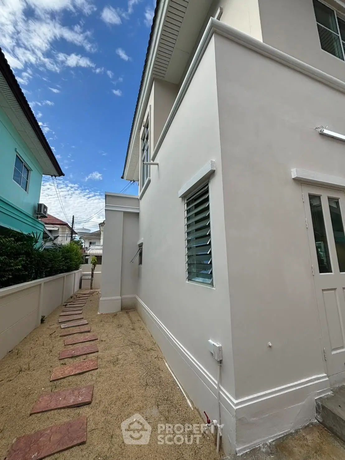 Modern two-story house exterior with clean lines and a side pathway, showcasing contemporary architecture.