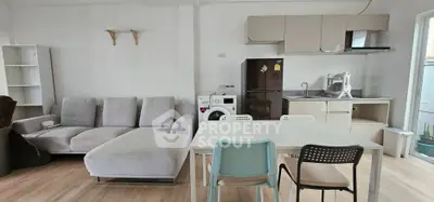 Modern open-plan living room with kitchen, featuring cozy sofa and dining area.