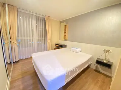 Spacious bedroom with modern decor and large window for natural light.