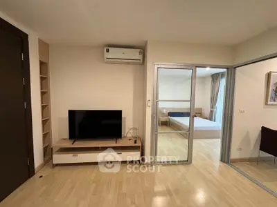 Modern apartment interior with living room and bedroom, featuring wooden flooring and sleek furniture.