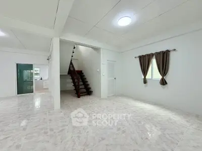 Spacious open-plan living area with modern staircase and natural light.