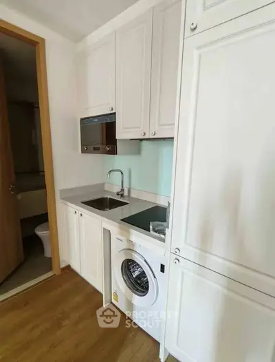 Compact kitchen with integrated washing machine and sleek cabinetry
