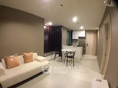 Modern open-layout living room with cozy seating and sleek kitchen area