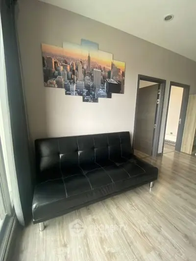 Modern living room with sleek black sofa and cityscape wall art, featuring stylish flooring and contemporary design.
