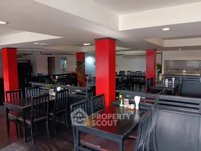 Spacious dining area with modern black furniture and vibrant red accents, perfect for gatherings.
