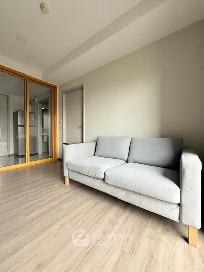 Modern living room with sleek gray sofa and wooden flooring, reflecting contemporary interior design.
