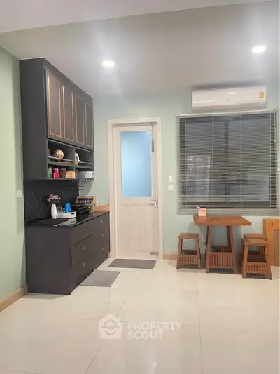 Modern kitchen with sleek cabinetry and dining area, featuring air conditioning and natural light.