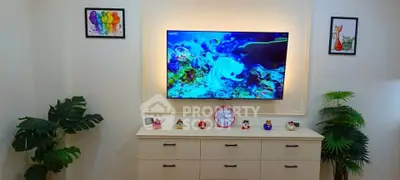 Charming living room with modern decor and vibrant wall art, featuring a sleek TV setup and stylish storage unit.