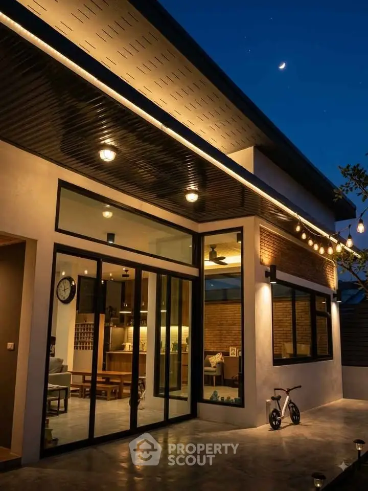 Modern home exterior with large glass doors and evening lighting
