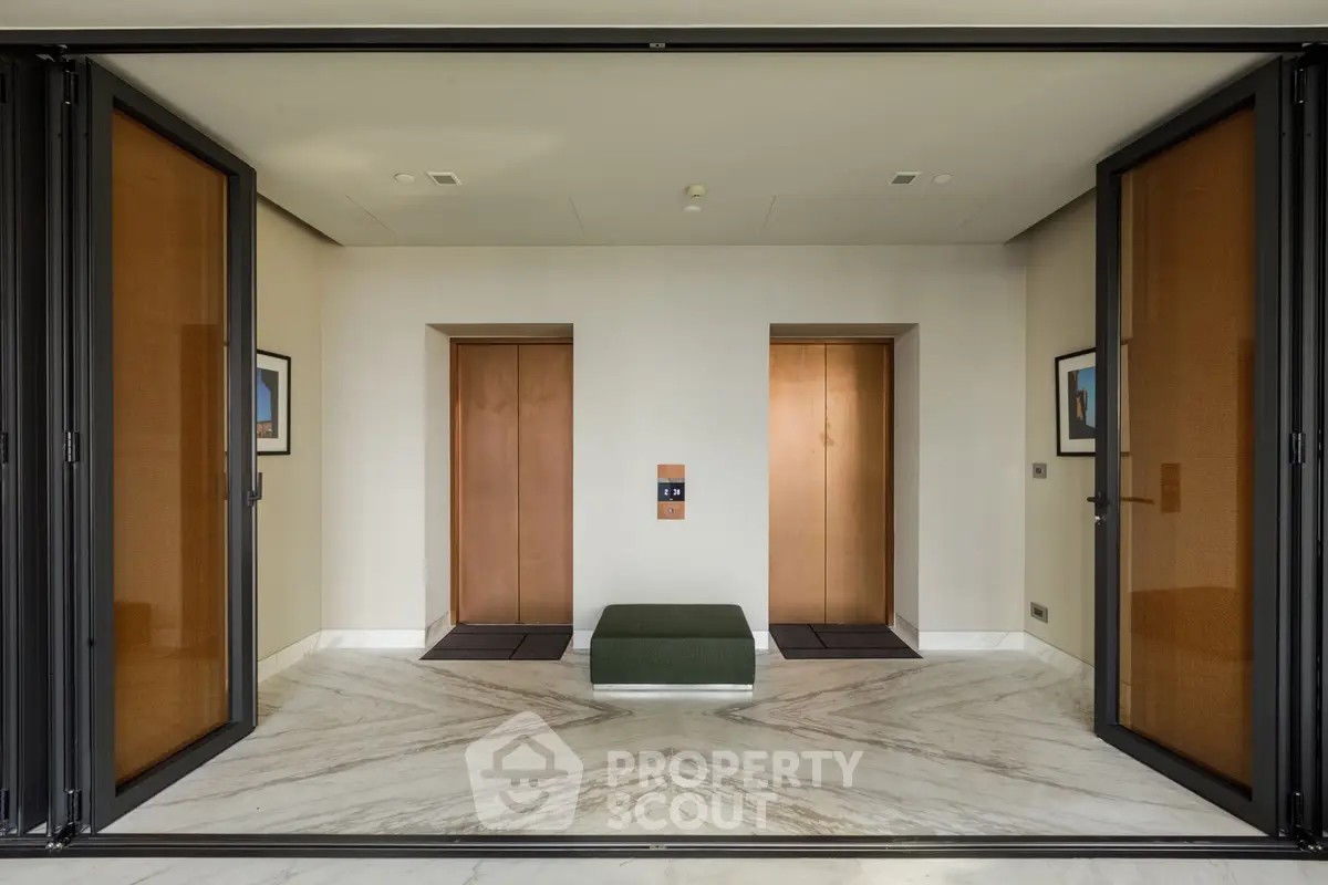 Elegant modern building entrance with dual elevators and marble flooring