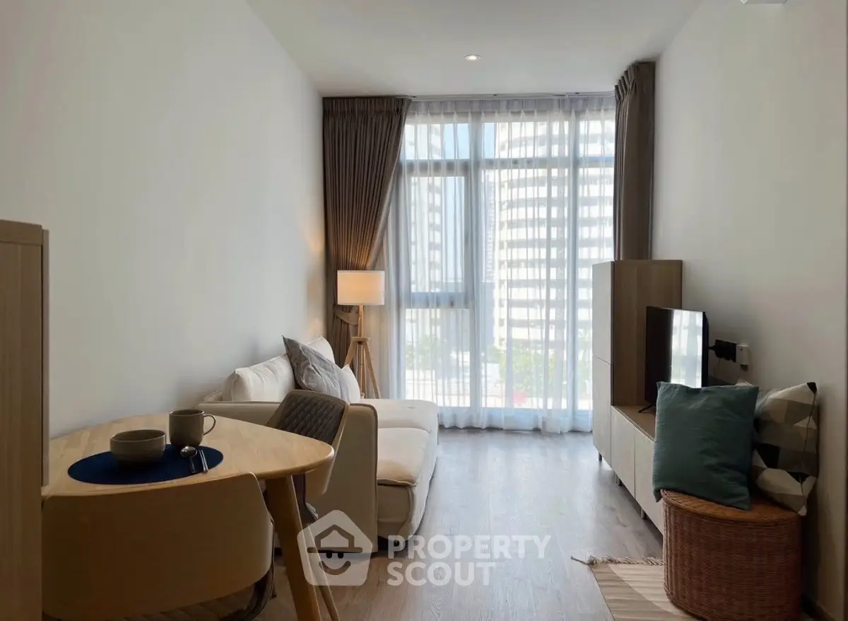 Modern living room with natural light, cozy seating, and stylish decor in a high-rise apartment.