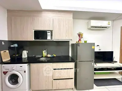 Modern kitchen with washing machine, microwave, and fridge in compact layout.